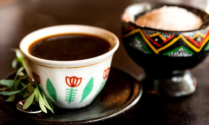 A small patterned cup of black coffee beside a woven basket