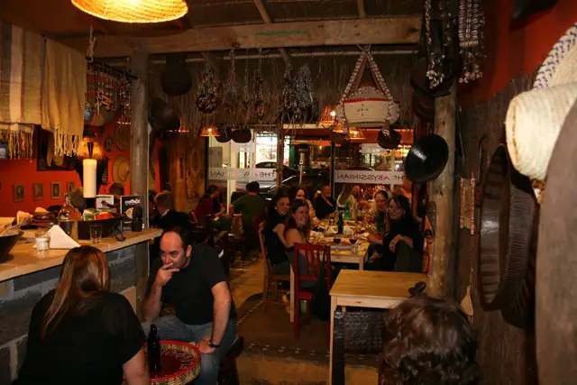 Guests sharing dinner under the thatched ceiling, with woven baskets and orange walls