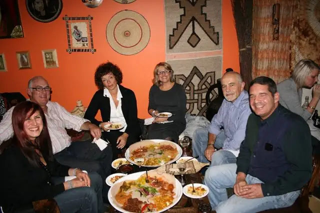 A group of friends smiling over platters in front of the basket wall
