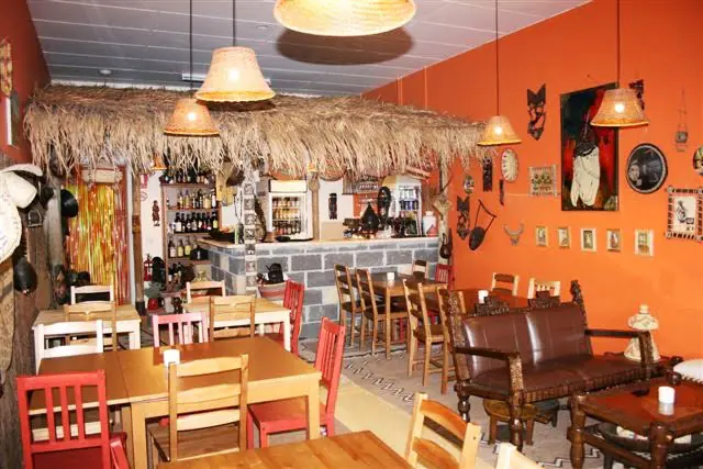 The bar and dining room with woven lampshades under a thatched ceiling