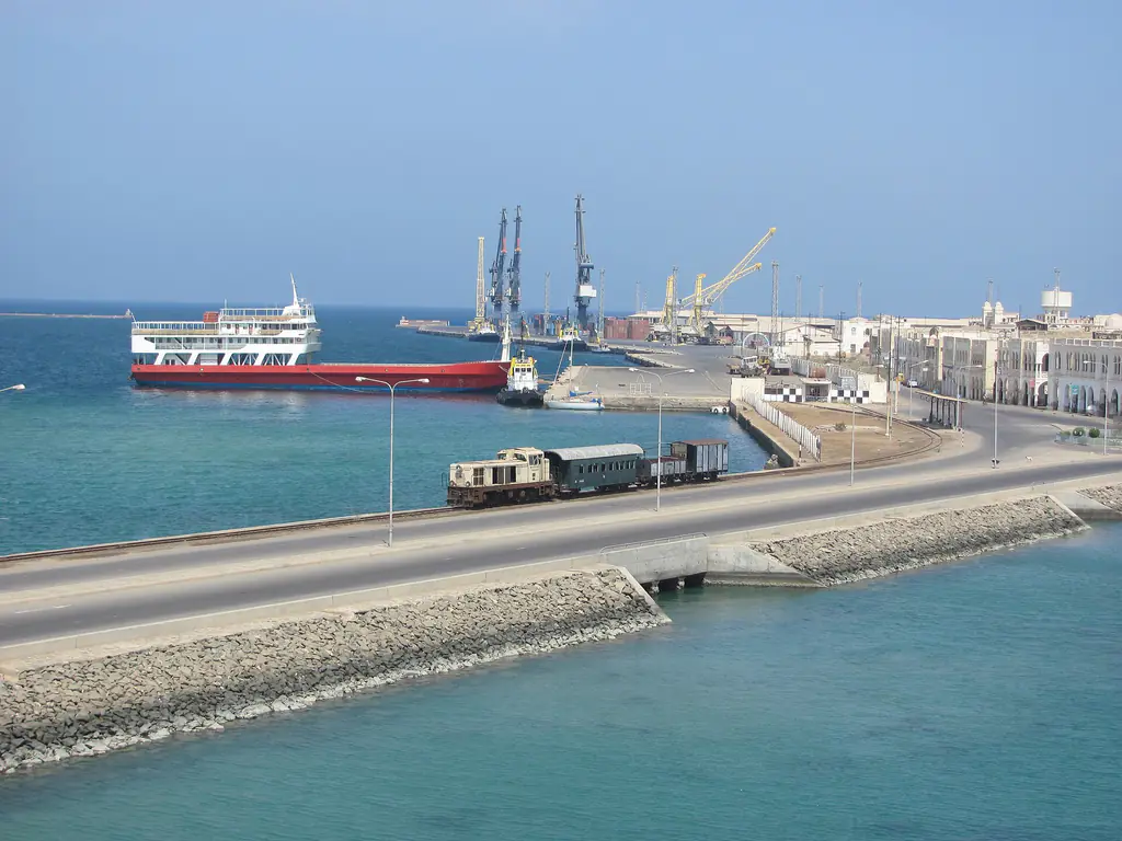 Massawa harbour: turquoise water, a ship at the wharf, cranes, and the little railway running along the causeway