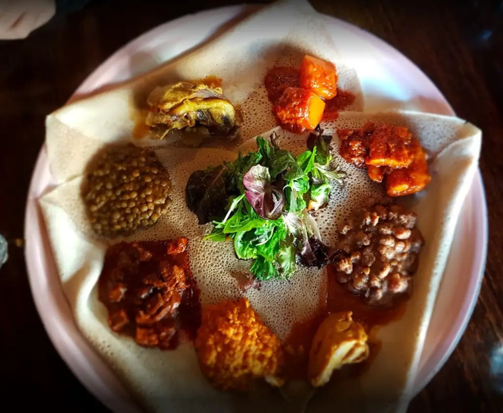 The mixed platter from above: lamb, chicken, fish, lentils, vegetables and salad arranged on injera