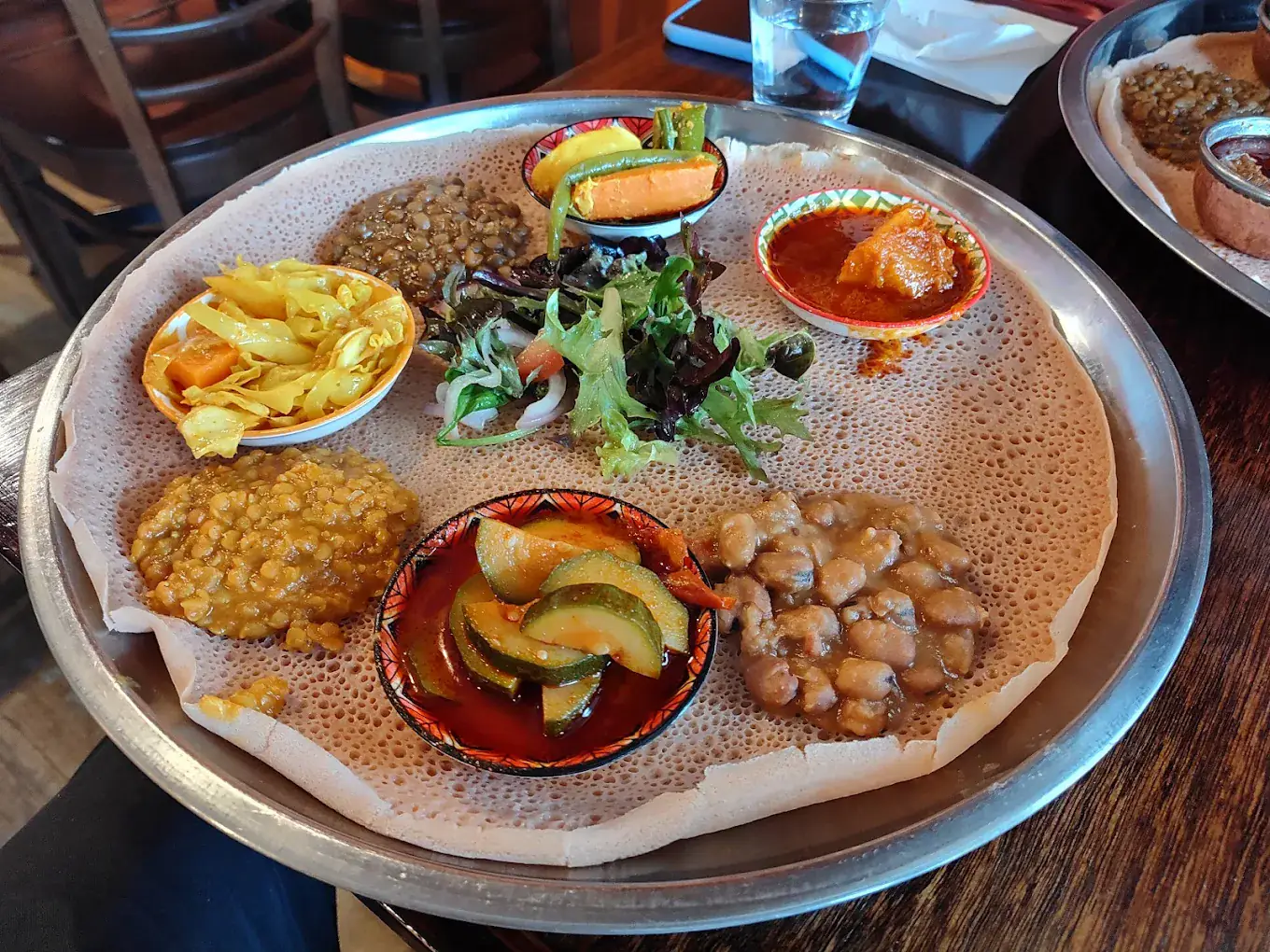 The veg platter: shiro, red lentils, green lentils, chickpeas, cabbage and carrot, zucchini in berbere, pumpkin and salad on a round of injera